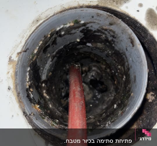 צינור אדום בתוך ניקוז מלוכלך